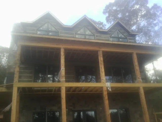 Dormers and porch framing on a large log home under construction — Roof Coating work by our crew in Snow Hill